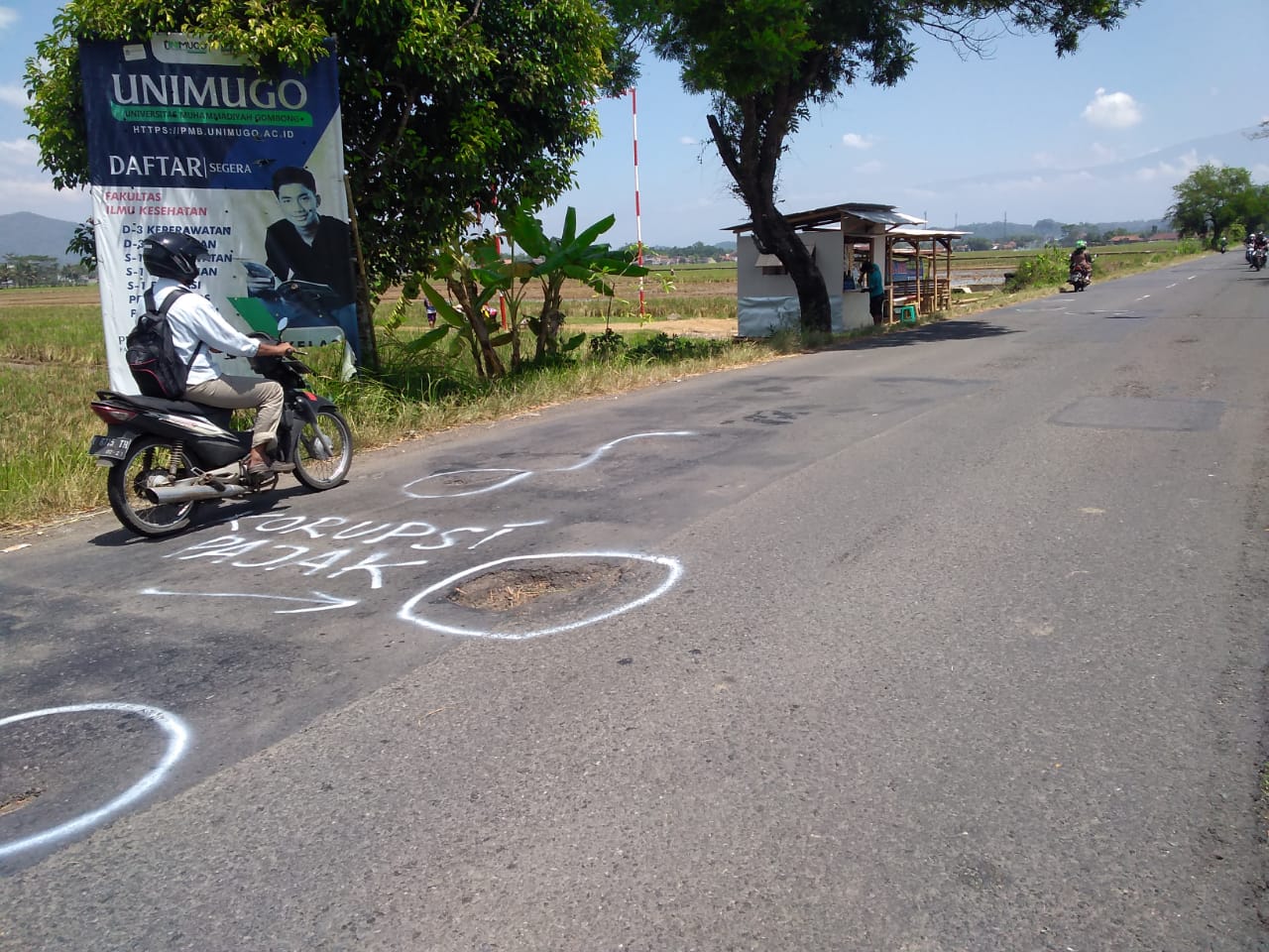 Tulisan KORUPSI PAJAK di Badan Jalan Berlubang Kabupaten Ruas Danaraja-Karangsawah